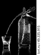 siphon with soda copulation on the table on a black background with a full glass, jet and drops. Стоковое фото, агентство Ingram Publishing / Фотобанк Лори