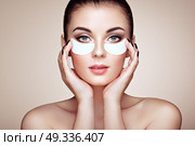 Portrait of Beauty Woman with eye Patches showing an effect of Perfect Skin. Beautiful Face of young Woman with clean Fresh Skin and bare shoulders on beige background. Brunette Spa Girl. Стоковое фото, агентство Ingram Publishing / Фотобанк Лори