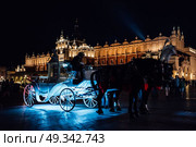 The old square of the night krakow with luminous horse-drawn carriages. Стоковое фото, агентство Ingram Publishing / Фотобанк Лори