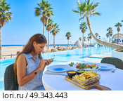 Young woman texting with smartphone chat on a swimming pool restaurant. Стоковое фото, агентство Ingram Publishing / Фотобанк Лори