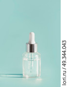 Cosmetic transparent liquid in glass bottle with dropper. Serum skin care product on light mint background, front view with copy space. Beauty product concept. Blank label for branding mock-up. Стоковое фото, агентство Ingram Publishing / Фотобанк Лори