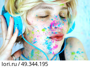 Young woman with paint in her face is listening to music . Стоковое фото, агентство Ingram Publishing / Фотобанк Лори