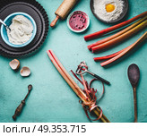 Rhubarb peeling.  Fresh red rhubarb stalks with peeler on kitchen table background with cooking and baking tools, top view. Seasonal food concept. Стоковое фото, агентство Ingram Publishing / Фотобанк Лори