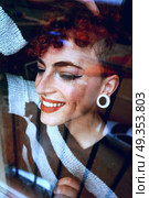 Beautiful and youthful redhead woman looking through a window . Стоковое фото, агентство Ingram Publishing / Фотобанк Лори