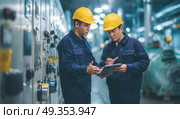 Two men in blue jackets and yellow hard hats are looking at a tablet. Стоковое AI-изображение, AI-художник Ярославский Максим / Фотобанк Лори