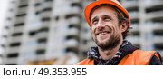 A construction worker wearing an orange vest and a hard hat smiles. Стоковое AI-изображение, AI-художник Ярославский Максим / Фотобанк Лори