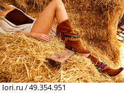 female legs with leather brown on straw bale. female legs with leather brown boots relaxed on straw bale barn. Стоковое фото, агентство Ingram Publishing / Фотобанк Лори