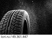 Snow sweeps up a winter tyre cover on a black background. Rubber in snow. Стоковое фото, агентство Ingram Publishing / Фотобанк Лори