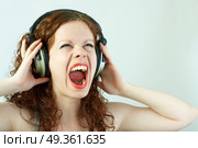 The girl in headphones shouts on a white background. Pleasure of a sound. Стоковое фото, агентство Ingram Publishing / Фотобанк Лори