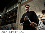 The criminal with threat holds in hands a chain in the thrown building  . The gangster  . Стоковое фото, агентство Ingram Publishing / Фотобанк Лори