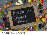 Colorful halloween candies on stone. Trick and treat letters in chalk on blackboard with colorful halloween candies on stone with copy space. Стоковое фото, агентство Ingram Publishing / Фотобанк Лори