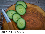 Cucumber slices in and olive wood board knife. Cucumber slices in and olive wood board with knife. Стоковое фото, агентство Ingram Publishing / Фотобанк Лори