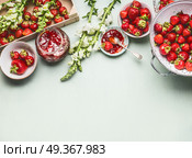 Homemade tasty strawberries jam in glass jar with summer flowers and fresh berries, bowls and spoon on table background, top view. Berries preserve concept, border. Стоковое фото, агентство Ingram Publishing / Фотобанк Лори