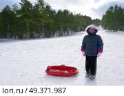 Kid girl with sled in a snowed mountain slope in a cold day. Стоковое фото, агентство Ingram Publishing / Фотобанк Лори