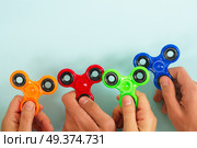 trendy fidget spinners - styled flat lay scene with hands holding generic design spinners. fidget spinner, popular relaxing toy, generic design. Стоковое фото, агентство Ingram Publishing / Фотобанк Лори