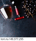 Red wine concept.  Glass with red wine,  bottle and red grape clusters on black rustic background, top view. Place for your design, text, article, advertisement or product. Стоковое фото, агентство Ingram Publishing / Фотобанк Лори