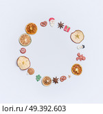 Christmas round circle fame or wreath made with dried fruits and anise stars and marzipan Christmas decor figures: Santa, tree, ginger man, snowman and balls on white background, top view, flat lay. Стоковое фото, агентство Ingram Publishing / Фотобанк Лори