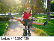 Acrobatic girl riding e-bike in a city park with red t-shirt foldable ebike. Стоковое фото, агентство Ingram Publishing / Фотобанк Лори