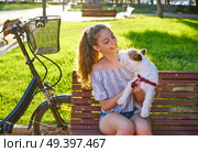 Girl with dog sitting in a park bench with turf grass background outdoor. Стоковое фото, агентство Ingram Publishing / Фотобанк Лори