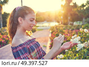 Girl portrait taking photos to a rose flower with smarphone. Стоковое фото, агентство Ingram Publishing / Фотобанк Лори