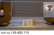 The double bed is covered with white sheets and a yellow bedspread. Pillows at the headboard. Wall sconces, lamps lit. The bedroom is ready for bed. Hotel. Стоковое фото, фотограф Вера Ивановна Кубарева / Фотобанк Лори