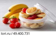 Delicious mini pancakes surrounded by fresh fruit at breakfast time. Вкусные мини-блинчики в окружении свежих фруктов во время завтрака. Стоковое AI-изображение, AI-художник Katsiaryna Repich / Фотобанк Лори