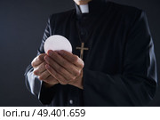 Communion wafer hostia priest in hands with cross. Стоковое фото, агентство Ingram Publishing / Фотобанк Лори