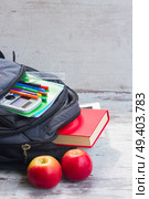 School backpack with supplies and two apples on white desktop. School backpack with supplies. Стоковое фото, агентство Ingram Publishing / Фотобанк Лори