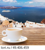 Cup of coffee with view of Thira and caldera of Santorini volcano with ships, Greece. Cup of coffee on  Santorini . Стоковое фото, агентство Ingram Publishing / Фотобанк Лори