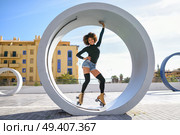 Young fit black woman on roller skates riding outdoors on urban street. Smiling girl with afro hairstyle rollerblading on sunny day. Стоковое фото, агентство Ingram Publishing / Фотобанк Лори