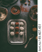 Healthy vegan homemade truffles making. Coated in cacao powder and almond flour truffle balls on dark rustic kitchen table background, top view. Стоковое фото, агентство Ingram Publishing / Фотобанк Лори