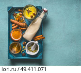 Golden turmeric milk on tray with ingredients: cardamom, turmeric, cinnamon, honey and ginger on blue background with copy space for your design, top view.  Immune boosting remedy , detox and dieting. Стоковое фото, агентство Ingram Publishing / Фотобанк Лори