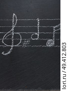 White  music notes with treble clef  on black backgound, verticel shot. Music notes on black. Стоковое фото, агентство Ingram Publishing / Фотобанк Лори