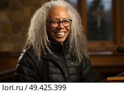 A woman with white hair and glasses smiles while standing at a podium. Стоковое AI-изображение, AI-художник Данила Большаков / Фотобанк Лори