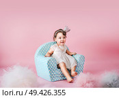 Little cute daughter sitting on an infantine armchair. Стоковое фото, агентство Ingram Publishing / Фотобанк Лори