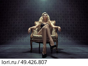 Dominating blond woman sitting on the vintage armchair. Стоковое фото, агентство Ingram Publishing / Фотобанк Лори