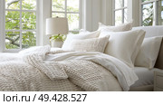 A bed made up with a white comforter and several fluffy pillows, creating a cozy and inviting atmosphere. Стоковое AI-изображение, AI-художник Данила Большаков / Фотобанк Лори