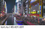 Osaka, Japan - Sep 22 2024, 4k, Panoramic view of Dotonbori river with a ship with tourists, a lot of people on embankment, there are a lot of advertising and illuminations on buildings, Osaka, Japan. Редакционное видео, видеограф Сергей Богомяко / Фотобанк Лори