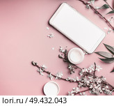 Smartphone mock up on pastel pink desktop background with cosmetic and blossom branches, top view. Beauty blog and female business concept. Стоковое фото, агентство Ingram Publishing / Фотобанк Лори