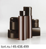 Various black and brown cosmetic product jars and bottles with branding mock up, standing on light table at wall background. Snail mucin cosmetic set or charcoal cosmetics. Modern facial skin care. Стоковое фото, агентство Ingram Publishing / Фотобанк Лори