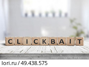 Clickbait word on a wooden sign in a living room with bright daylight. Стоковое фото, агентство Ingram Publishing / Фотобанк Лори