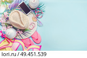 Summer beach outfit accessories. Girl set. Woman straw hat, swimsuit bikini, flipflop, sunglasses and smart phone with palm leaves and coconut drinks on blue background, top view. Tropical vacation. Стоковое фото, агентство Ingram Publishing / Фотобанк Лори