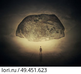 Surrealistic image as a man, with a bag in his back, stand in a foggy street below a huge squeezing rock. Life pressure and stress concept. Стоковое фото, агентство Ingram Publishing / Фотобанк Лори