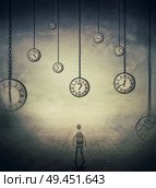 Surrealistic image with a man lost in time, standing in a foggy street in front of huge clocks set to different times. Hour perception and time travel concept. Стоковое фото, агентство Ingram Publishing / Фотобанк Лори