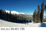 Scenic view of group of skiers on Bansko ski slope with blue sky background. Pirin mountains, Bulgaria. Стоковое фото, агентство Ingram Publishing / Фотобанк Лори