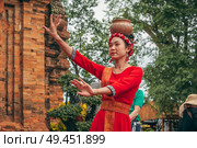 Vietnamese women in traditional red clothes dance in the towers of Nagar Cham in Asia. Nha Trang, Vietnam - December 18, 2024. Редакционное фото, фотограф Корчагина Анастасия / Фотобанк Лори