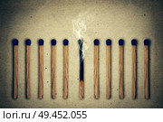 Extinguished, burnt match between a row of whole, new matches. Стоковое фото, агентство Ingram Publishing / Фотобанк Лори
