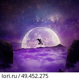 Boy with angel wings balance on a wire over a chasm riding a bicycle. Self overcoming and risk taking concept. Full moon night background over the clouds. Стоковое фото, агентство Ingram Publishing / Фотобанк Лори