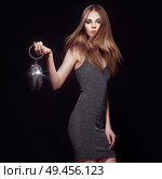 Beautiful young woman in Little black dress. Girl posing on a black background. Blonde girl with long healthy and shiny hair. Care and Beauty. Fashion photo. Glamour lady with a handbag of shiny gems. Стоковое фото, агентство Ingram Publishing / Фотобанк Лори