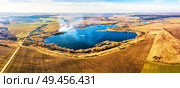 Spring agricultural fields. Smoke on the water and blue lake panorama. Winter crops and plowed field. Spring countryside aerial landscape. Dirt roads and village. Belarus. Стоковое фото, агентство Ingram Publishing / Фотобанк Лори